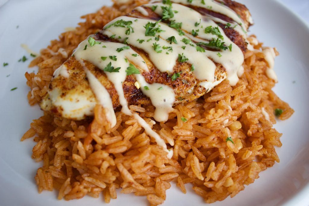 Poulet doré nappé d'une sauce au fromage, sur un riz